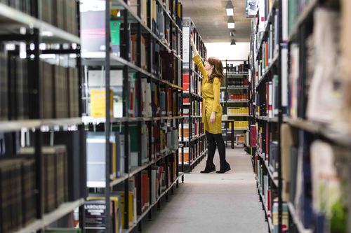 Bibliothek Frau am Bücherregal Thema Promotion an KAT-Hochschulen