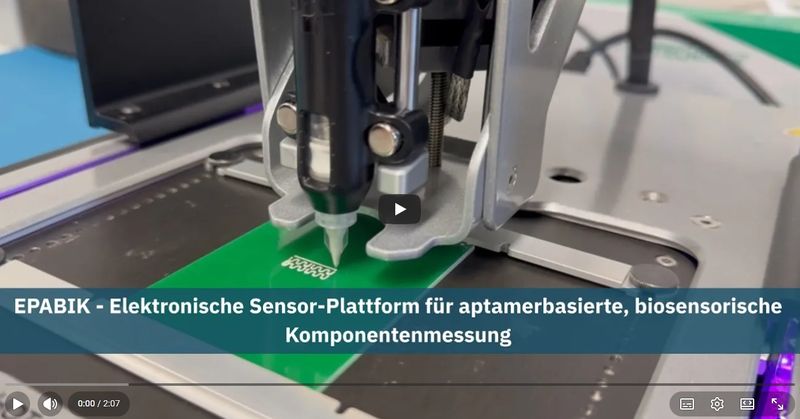 Ein Gerät bringt durch eine Düse eine weiße Flüssigkeit auf eine grüne Platte auf.