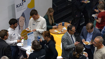 Mehrere Personen stehen in verschiedenen Gruppen zusammen und sprechen miteinander.