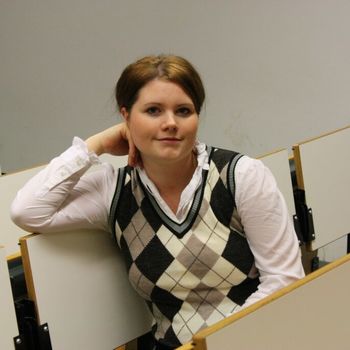 Porträtbild zeigt junge Frau in Stuhlreihe eines Hörsaals