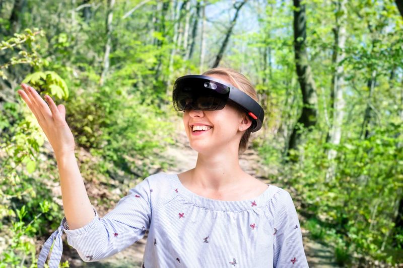 Eine junge Frau vor Wald-Hintergrund mit einer Hololens