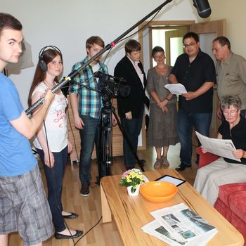 Gruppe von Menschen stehen bei Filmaufnahmen in einem Wohnzimmer