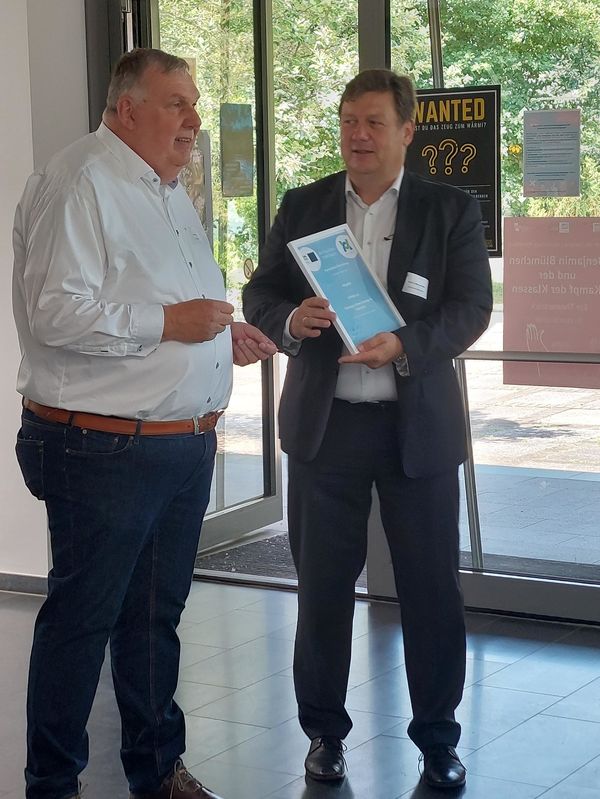Das Bild zeigt Axel Klug, der Prof. Dr. Markus Krabbes an der Hochschule Merseburg eine Mitgliedsurkunde übergibt.
