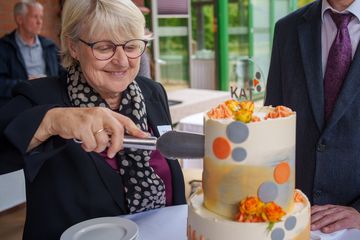 Eine Frau schneidet eine Torte an.
