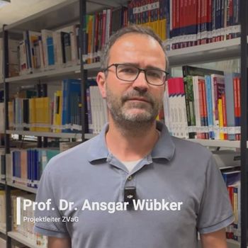 Ein Mann steht vor einem Bücherregal. Sein Name Prof. Dr. Ansgar Wübker ist eingeblendet.